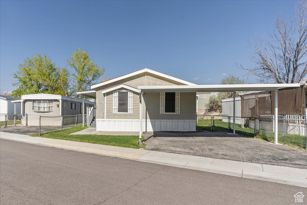 Manufactured / mobile home with an attached carport, fence, a gate, and aphalt driveway