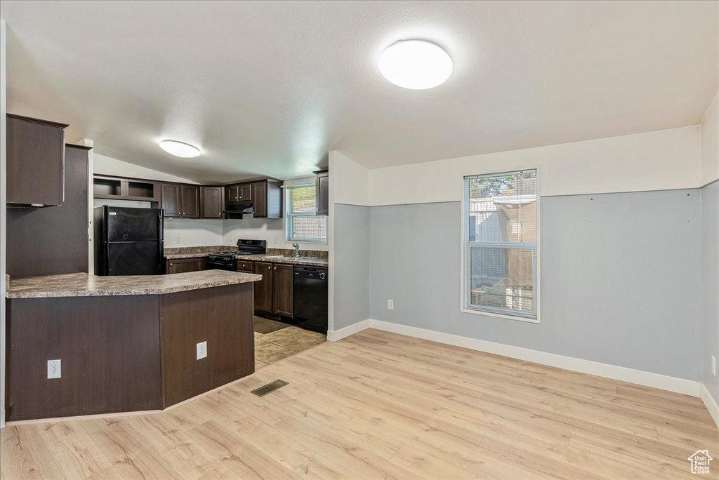 Kitchen with dark brown cabinets, a peninsula, light wood-type flooring, visible vents, and black appliances