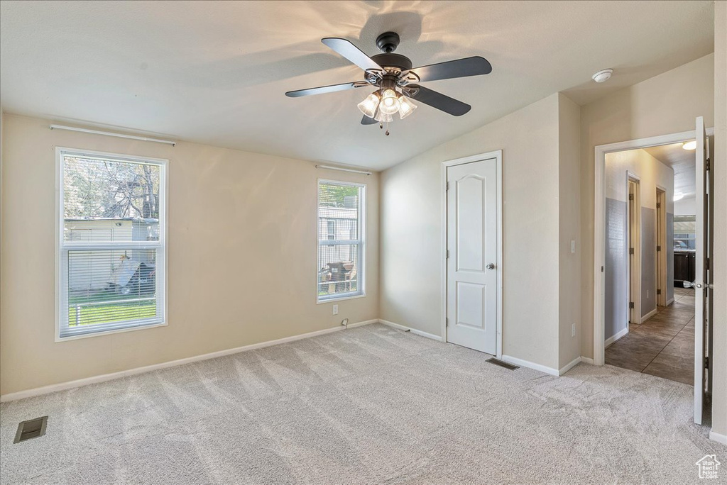 Unfurnished bedroom featuring carpet flooring, baseboards, visible vents, and vaulted ceiling