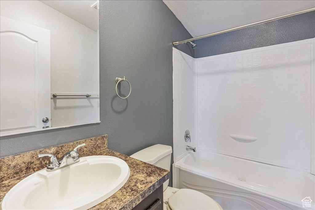 Full bathroom with toilet, a textured wall, shower / tub combination, and vanity