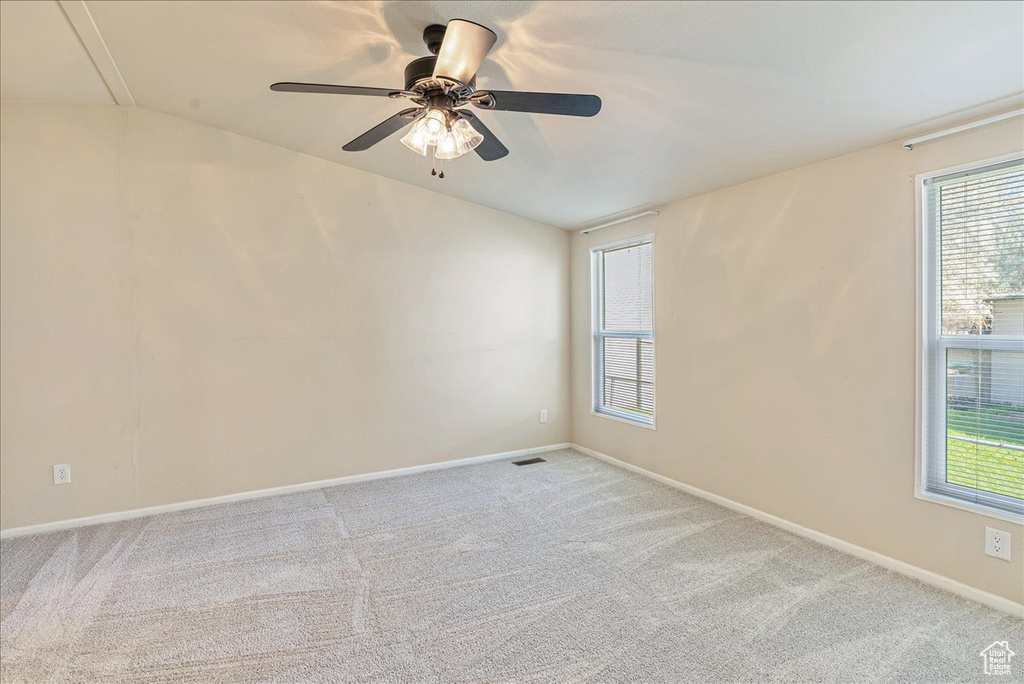 Empty room with carpet flooring, visible vents, and a healthy amount of sunlight
