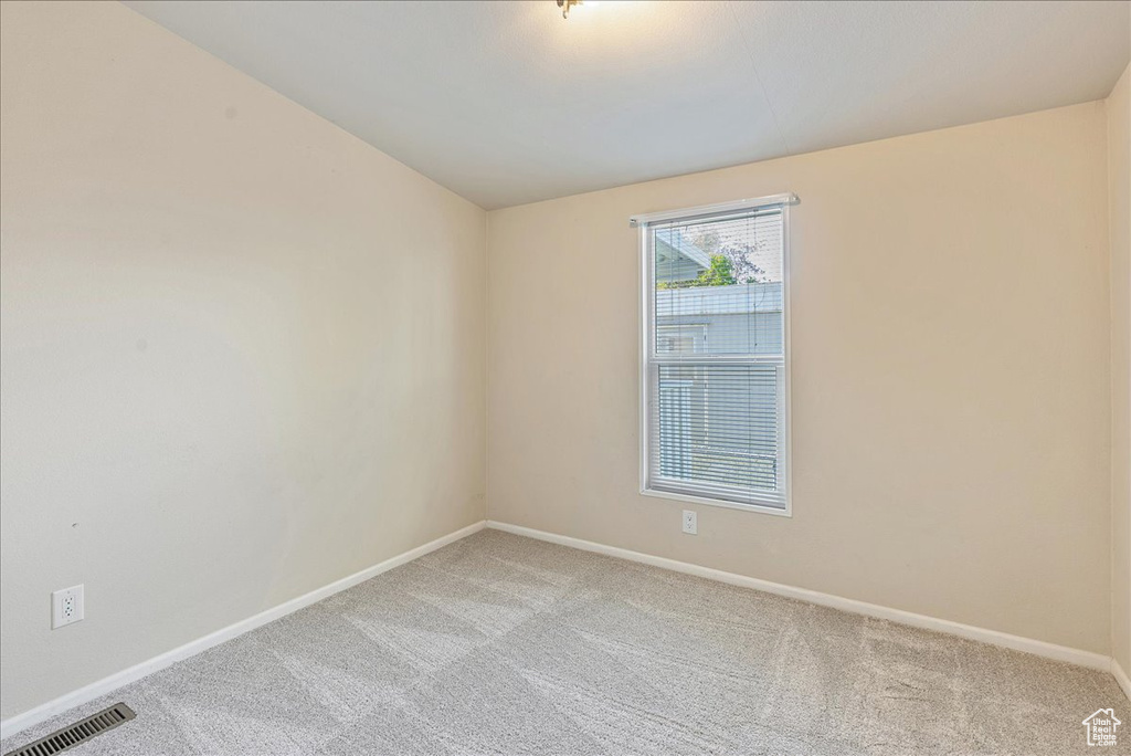 Unfurnished room with baseboards, visible vents, and light carpet