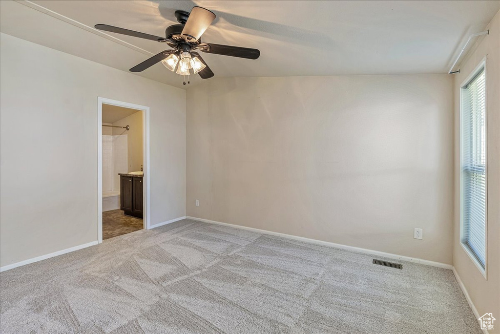 Spare room featuring visible vents, a ceiling fan, baseboards, and light carpet