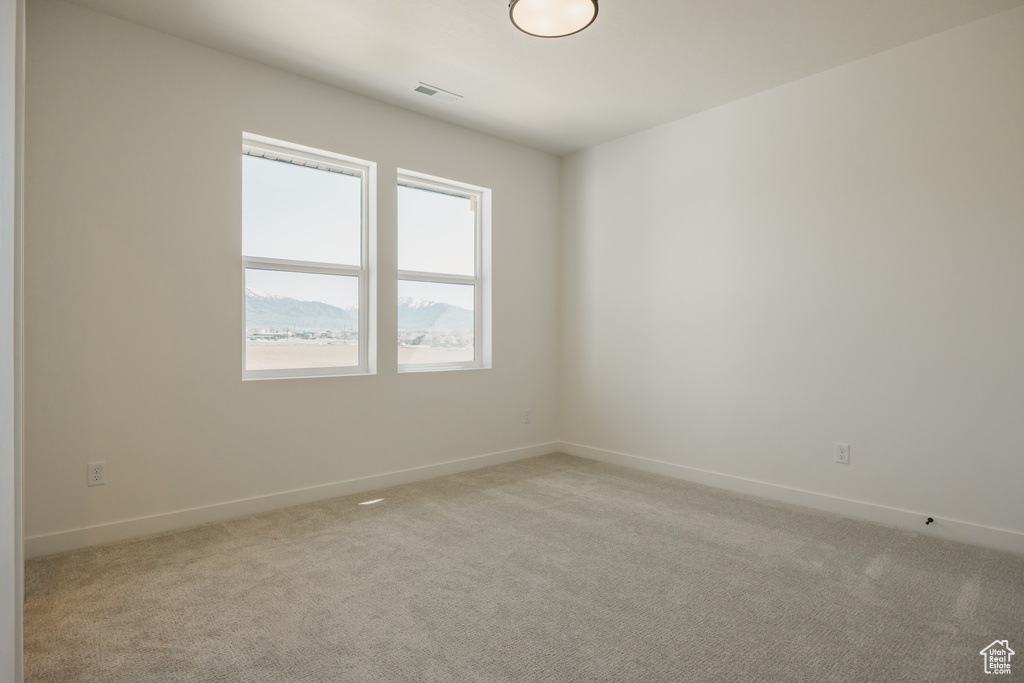 Unfurnished room featuring baseboards and light carpet
