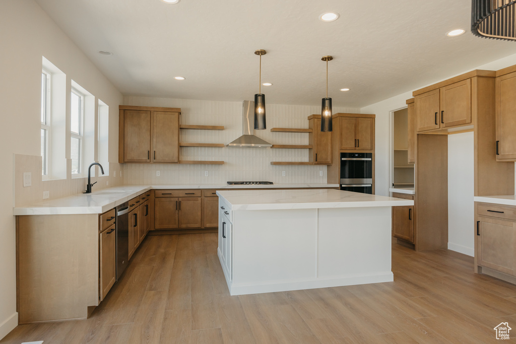 Kitchen with wall chimney exhaust hood, open shelves, light wood-type flooring, a sink, and recessed lighting