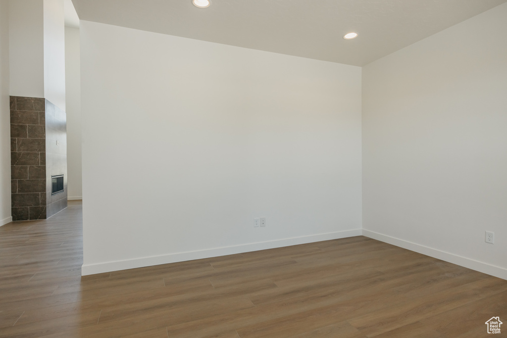 Unfurnished room featuring light wood-style flooring, baseboards, recessed lighting, and a tiled fireplace