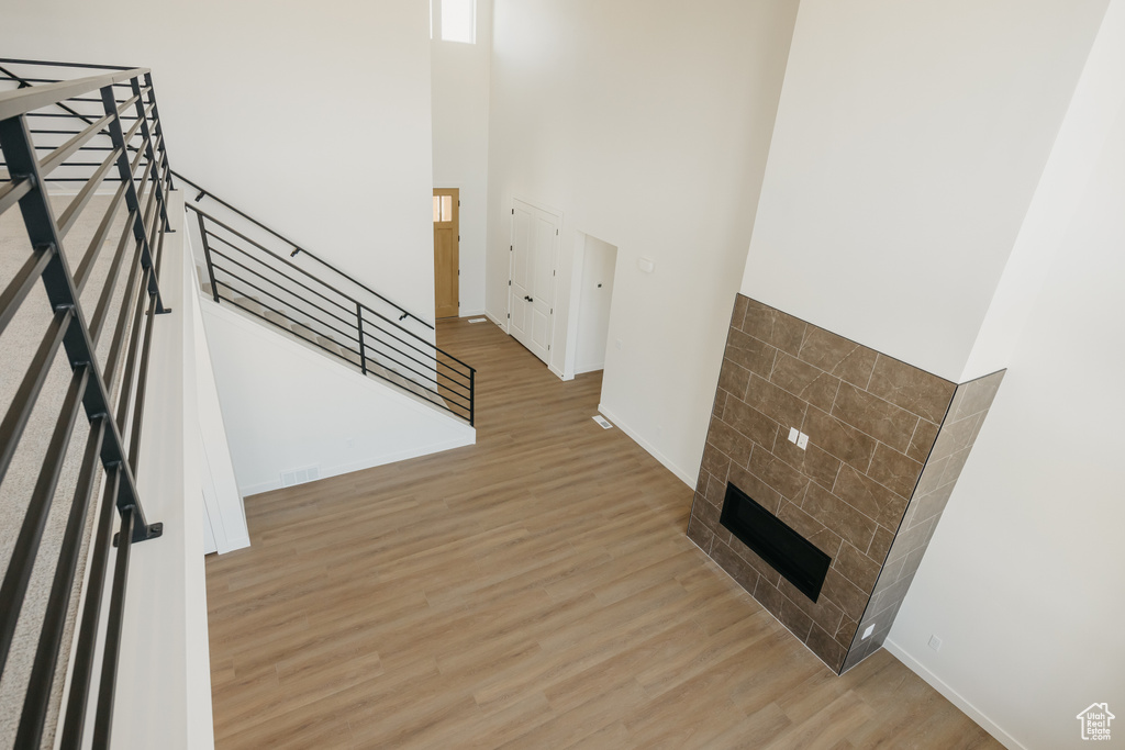 Unfurnished living room with wood finished floors, a high ceiling, baseboards, and a fireplace