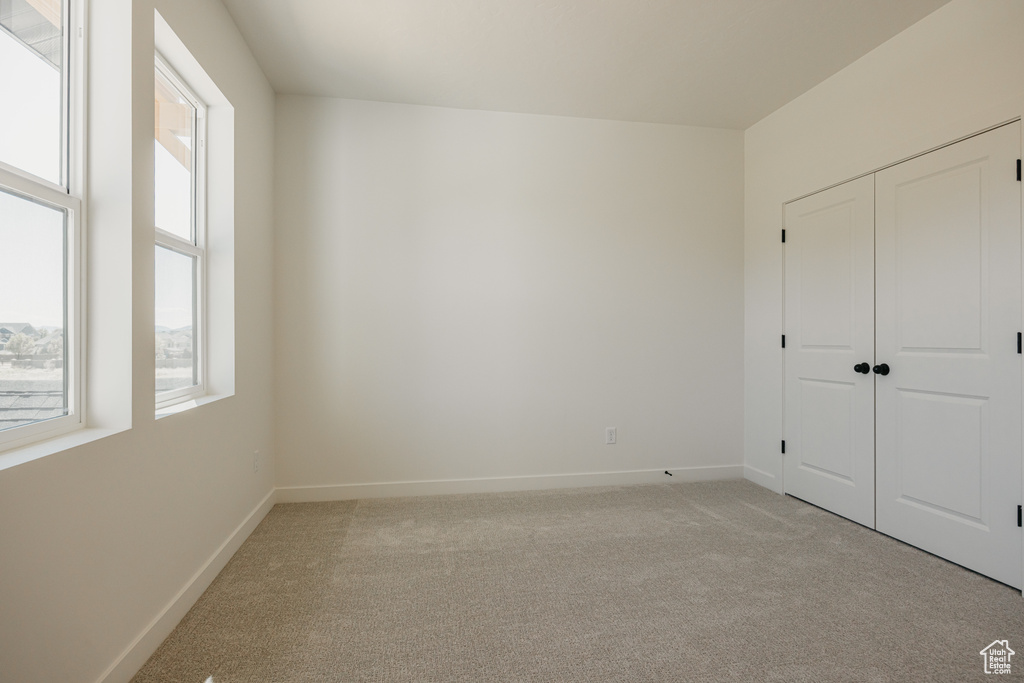 Unfurnished bedroom with light carpet, baseboards, and a closet