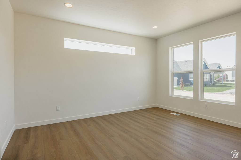 Empty room with wood finished floors, baseboards, and recessed lighting