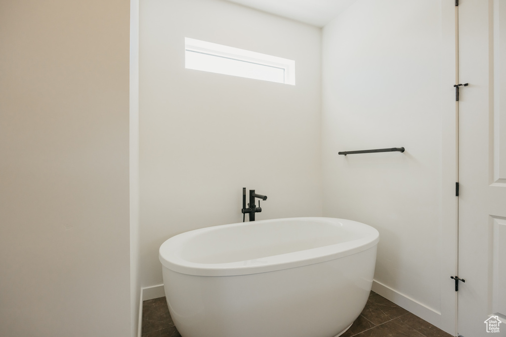 Bathroom with a freestanding bath, baseboards, and tile patterned floors