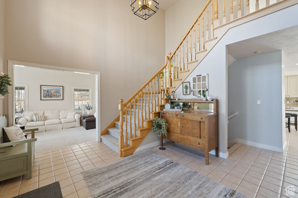 Foyer entrance featuring stairs, a high ceiling, baseboards, and tile patterned flooring