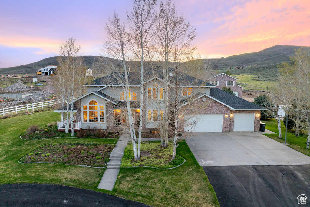 Traditional-style house with an attached garage, a lawn, fence, and concrete driveway