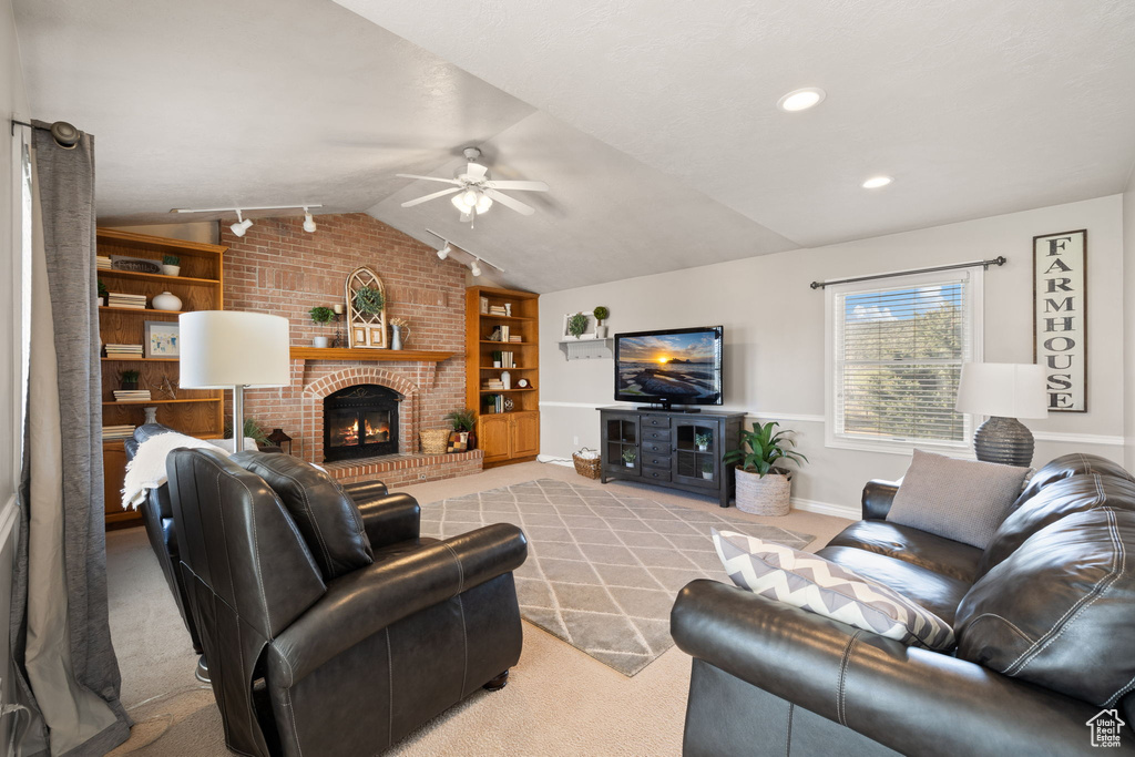 Living area featuring ceiling fan, carpet, built in shelves, and lofted ceiling