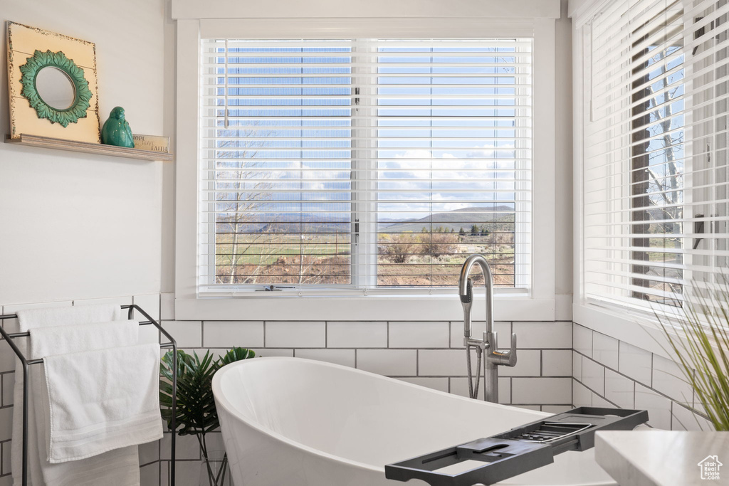 Full bathroom featuring a freestanding tub, tile walls, and wainscoting