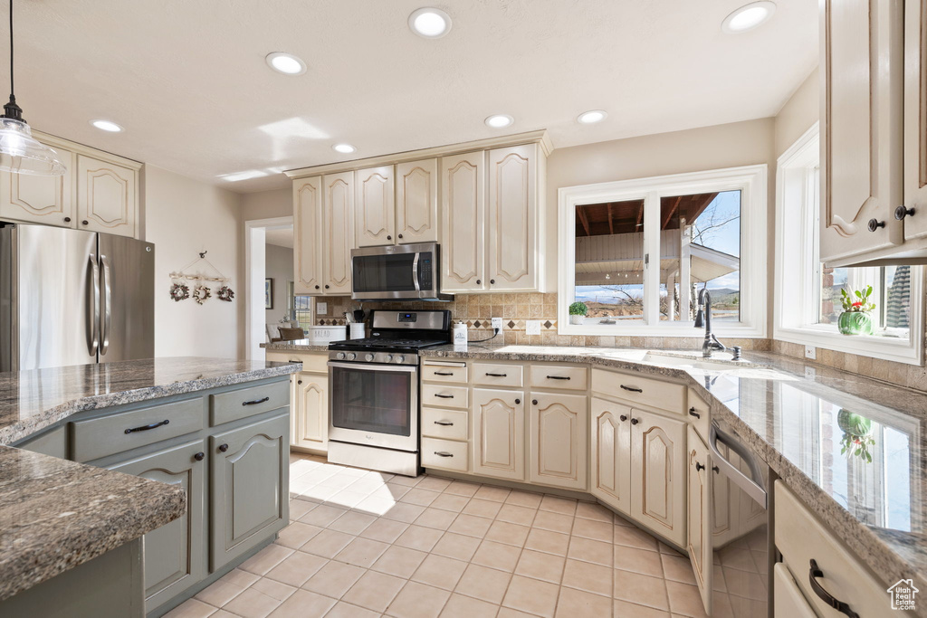 Kitchen featuring stainless steel appliances, hanging light fixtures, cream cabinetry, and recessed lighting
