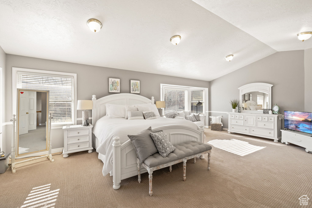 Bedroom with baseboards, light colored carpet, and vaulted ceiling