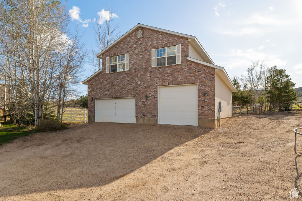 View of side of home featuring a garage, driveway, and brick siding