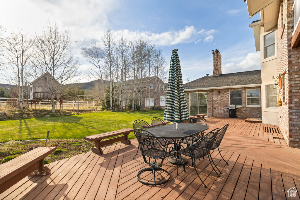 Wooden terrace with a yard, fence, and outdoor dining space