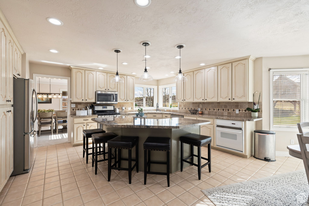 Kitchen with tasteful backsplash, stainless steel appliances, light tile patterned flooring, and a wealth of natural light