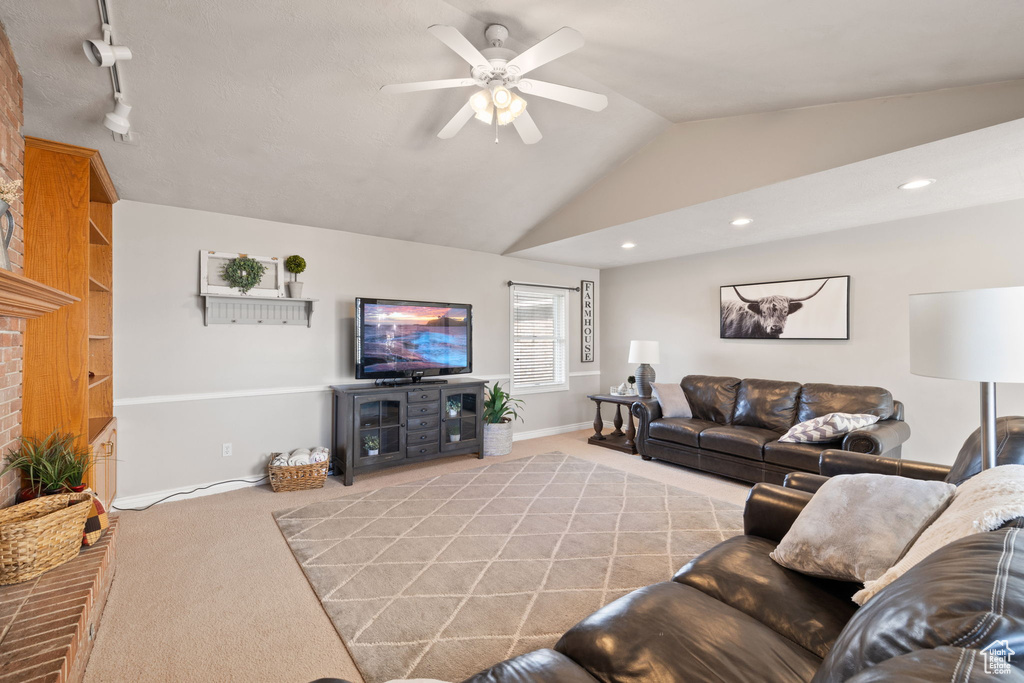 Living room featuring a ceiling fan, light colored carpet, a brick fireplace, baseboards, and lofted ceiling