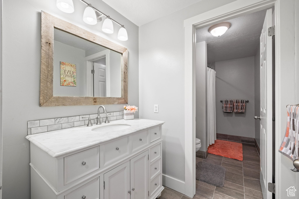 Full bathroom featuring baseboards, curtained shower, toilet, and vanity