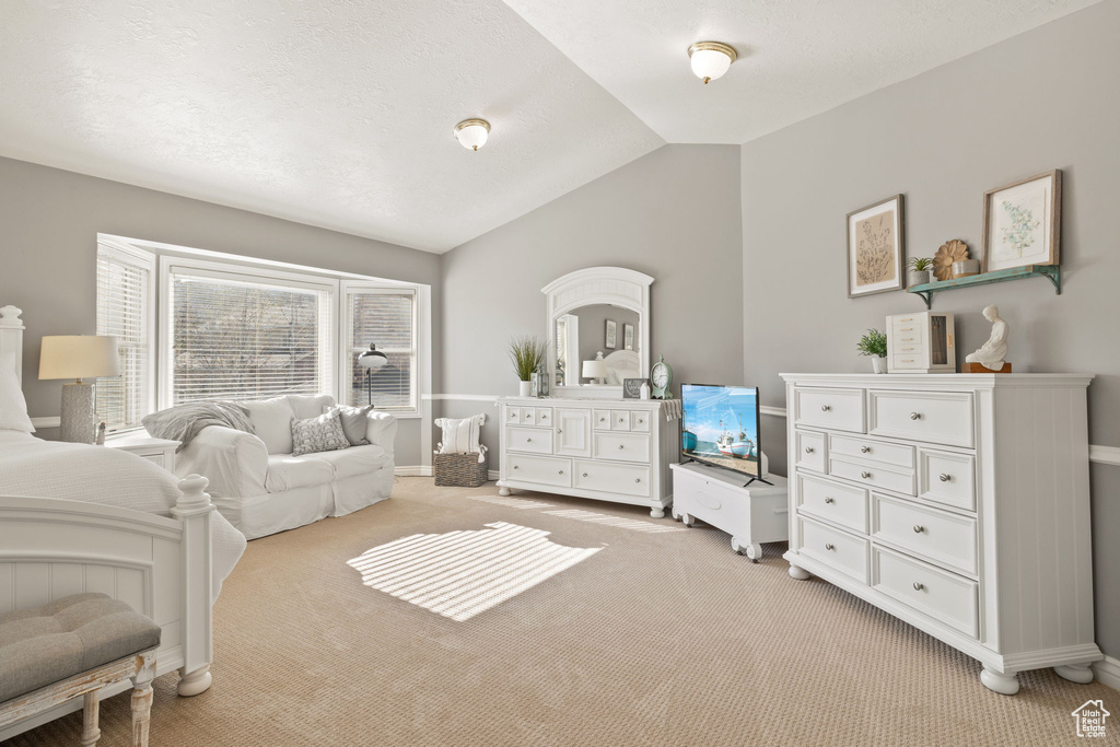 Bedroom featuring baseboards, vaulted ceiling, and light carpet