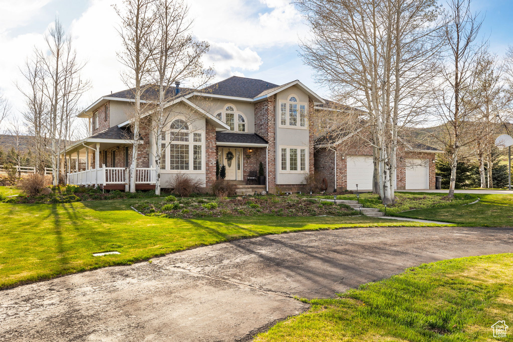 View of front of home featuring brick siding, a garage, a front yard, and stucco siding
