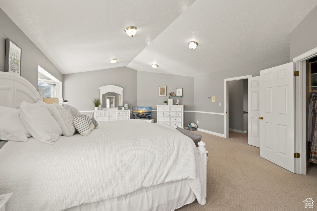 Bedroom featuring baseboards, lofted ceiling, and light carpet