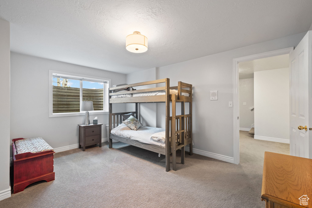 Carpeted bedroom featuring a textured ceiling and baseboards