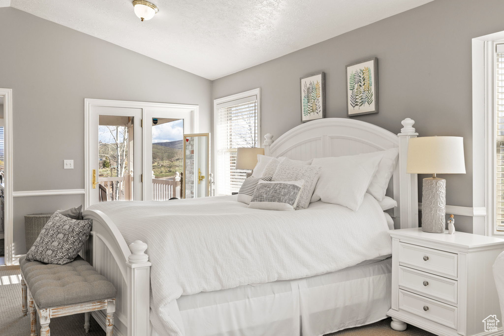 Bedroom featuring access to outside, carpet flooring, and lofted ceiling