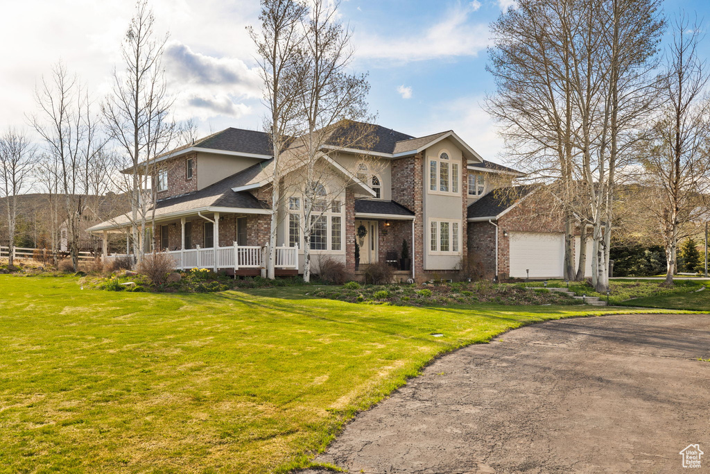 View of front of home featuring brick siding, a shingled roof, covered porch, and a front yard