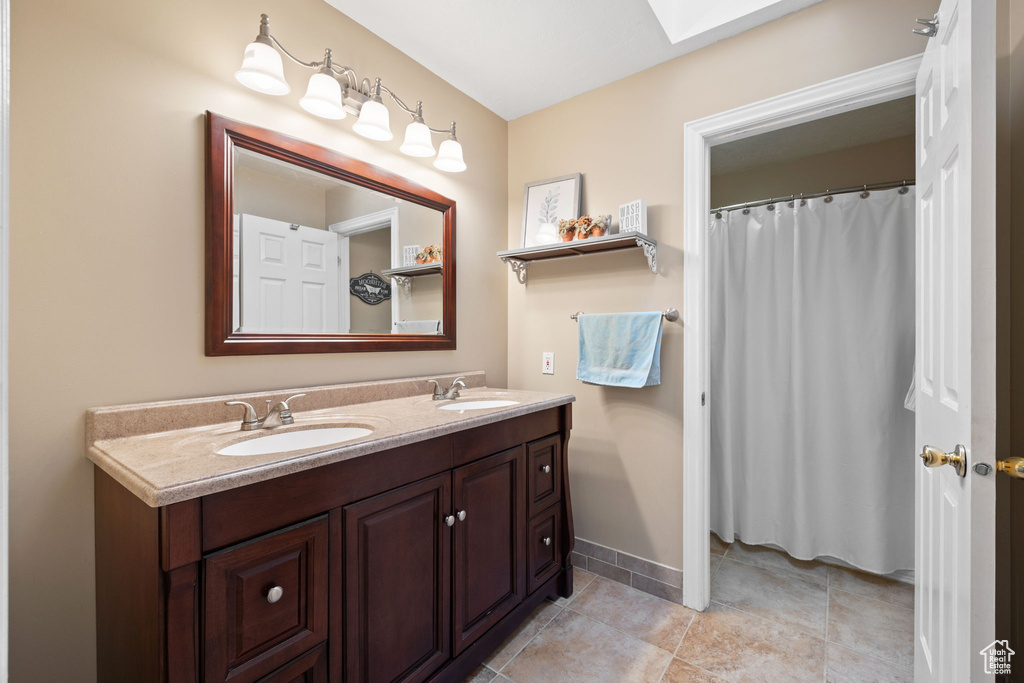 Full bathroom featuring a sink, baseboards, tile patterned flooring, and double vanity