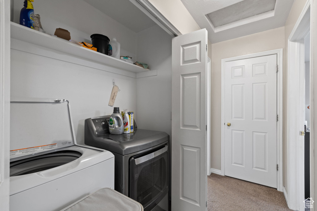 Washroom featuring laundry area, light carpet, and washing machine and clothes dryer