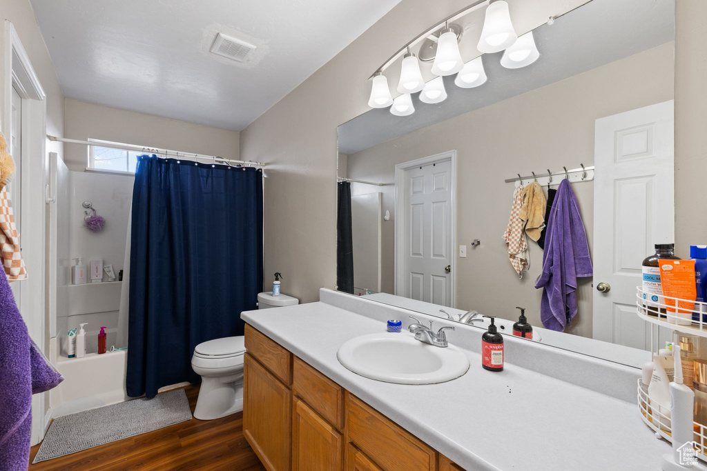 Full bathroom featuring vanity, toilet, shower / bath combination with curtain, wood finished floors, and visible vents