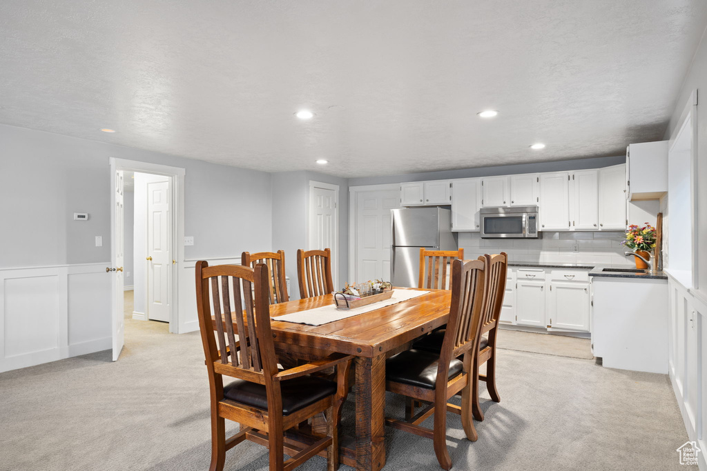 Dining room with a wainscoted wall, recessed lighting, and light colored carpet