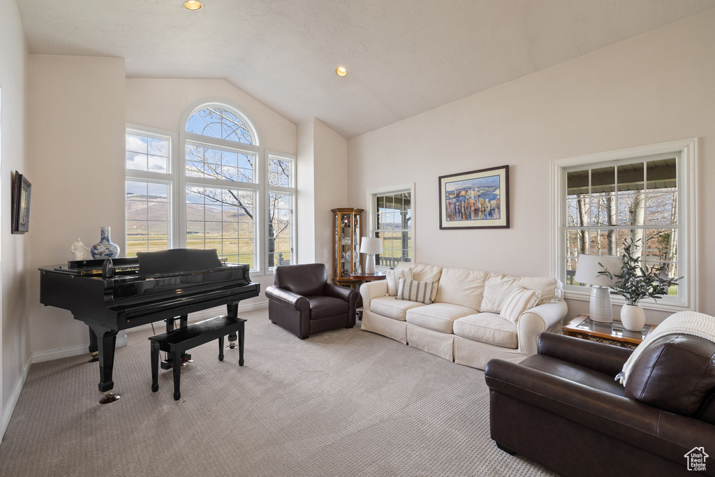 Living area featuring recessed lighting, baseboards, high vaulted ceiling, and light colored carpet