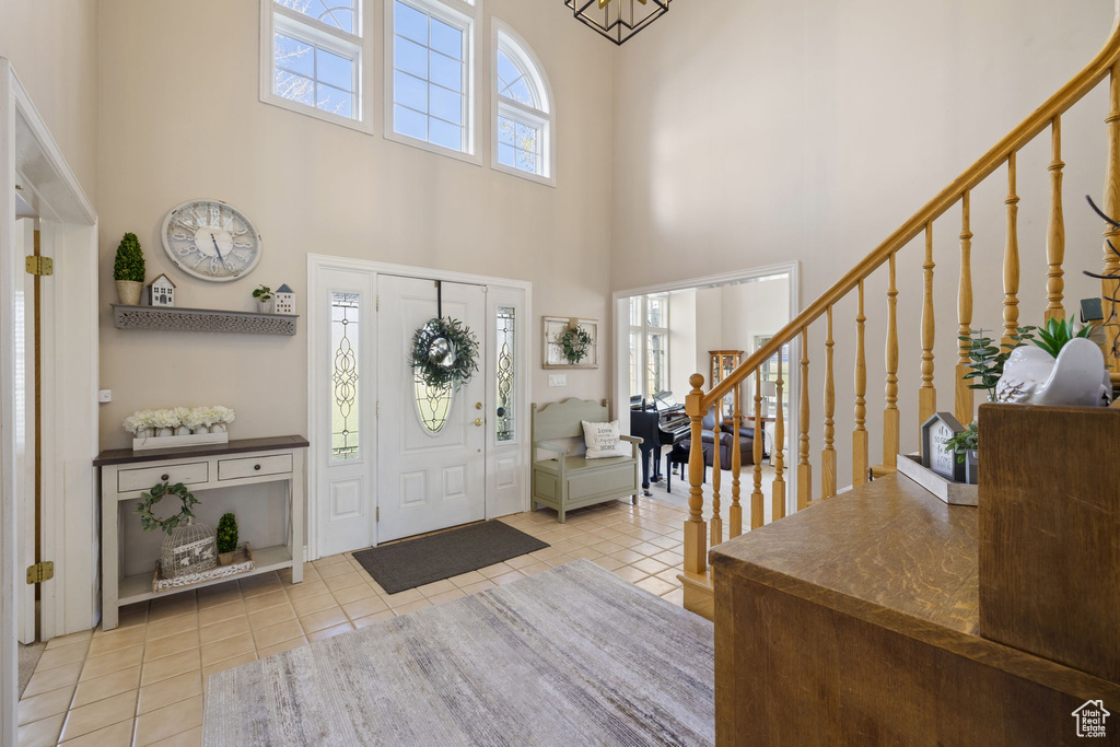 Tiled foyer entrance featuring stairs and a high ceiling