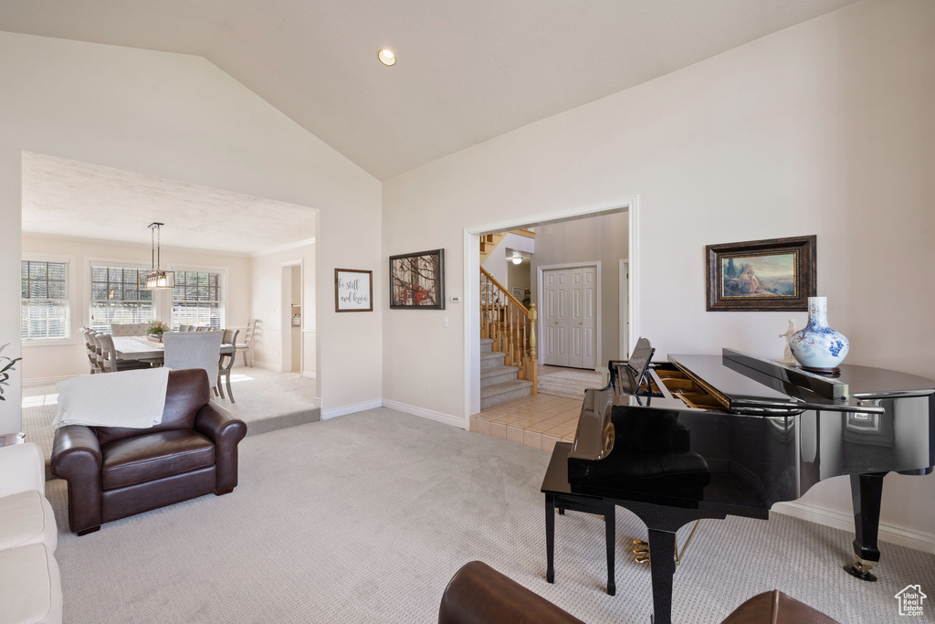 Living room featuring high vaulted ceiling, baseboards, light carpet, and stairs