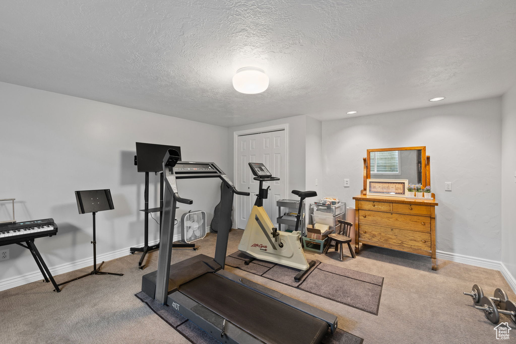 Workout area featuring carpet floors, a textured ceiling, baseboards, and recessed lighting