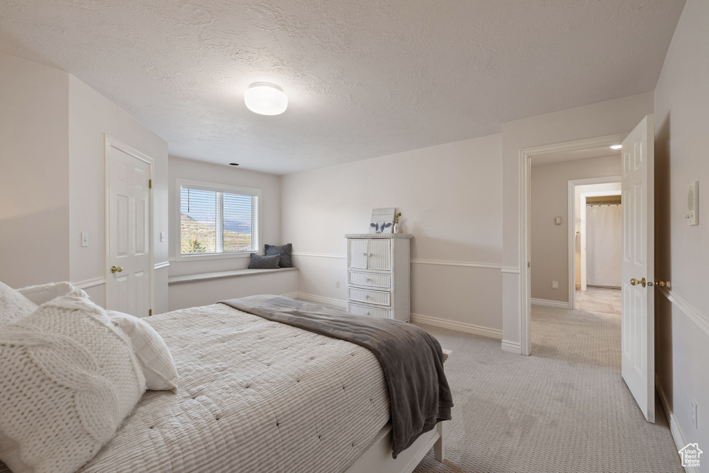 Bedroom with light colored carpet, a textured ceiling, and baseboards