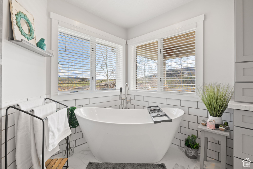 Full bath featuring a freestanding bath, tile walls, and marble finish floor