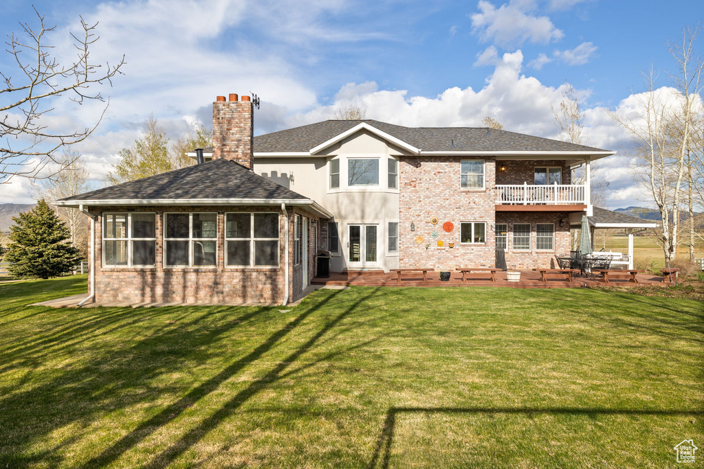 Back of property featuring a lawn, a patio, and brick siding