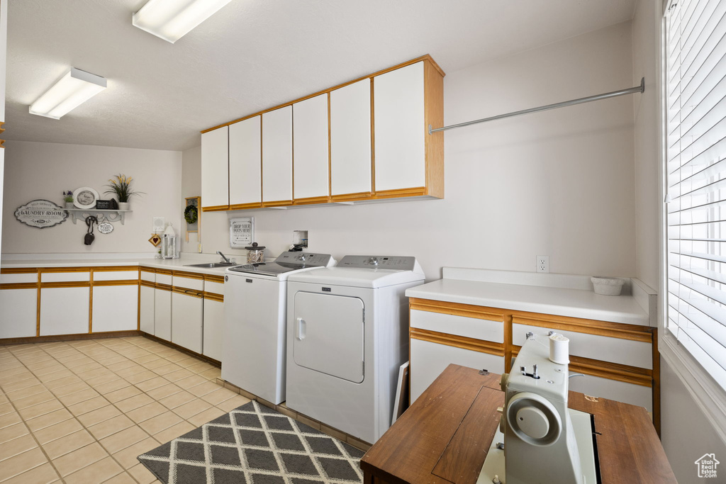 Laundry room featuring cabinet space, plenty of natural light, light tile patterned floors, and washer and dryer