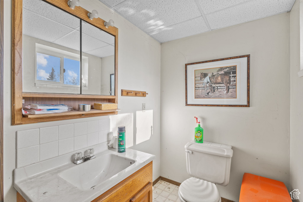 Bathroom with vanity, toilet, tile patterned floors, a paneled ceiling, and baseboards
