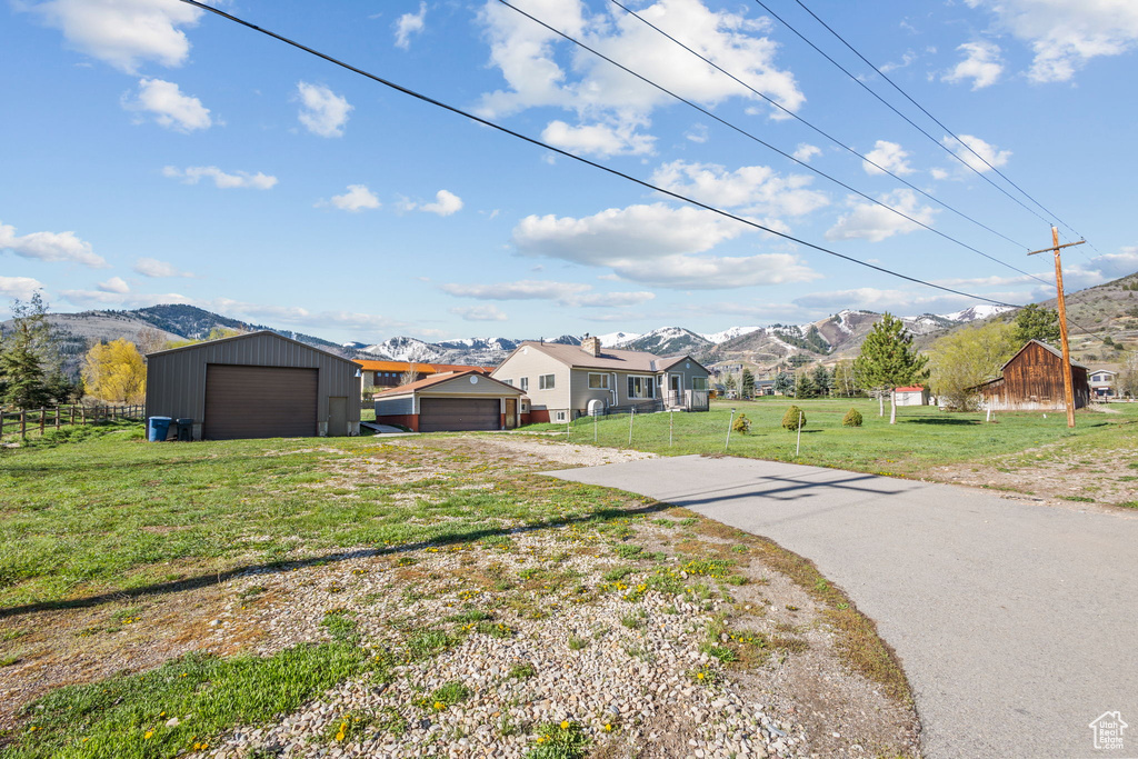 View of front of property featuring driveway, fence, a mountain view, and a front lawn