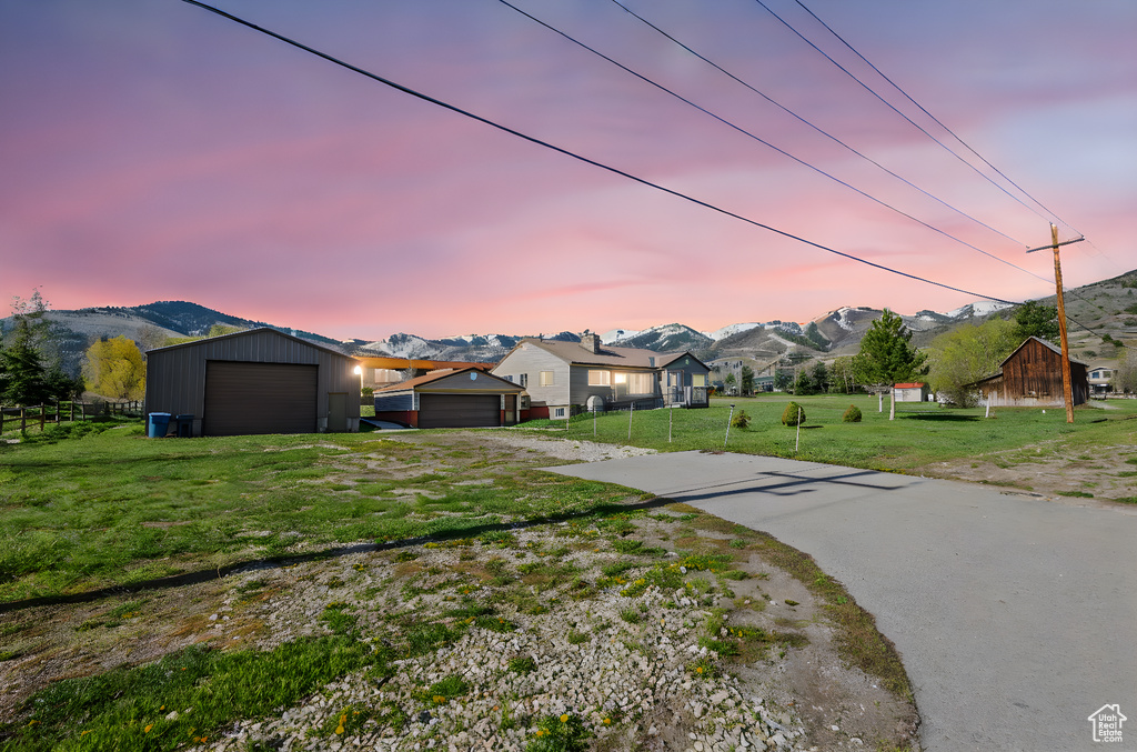 View of front of home featuring dirt driveway, an outbuilding, fence, a mountain view, and a yard