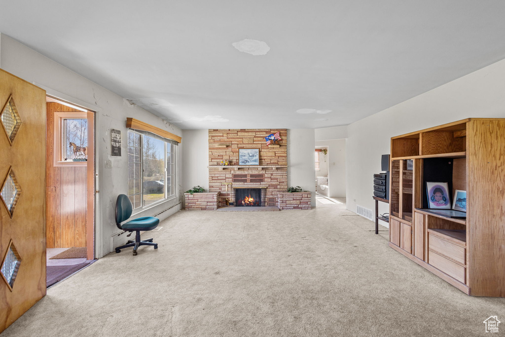 Carpeted living area with a stone fireplace and visible vents