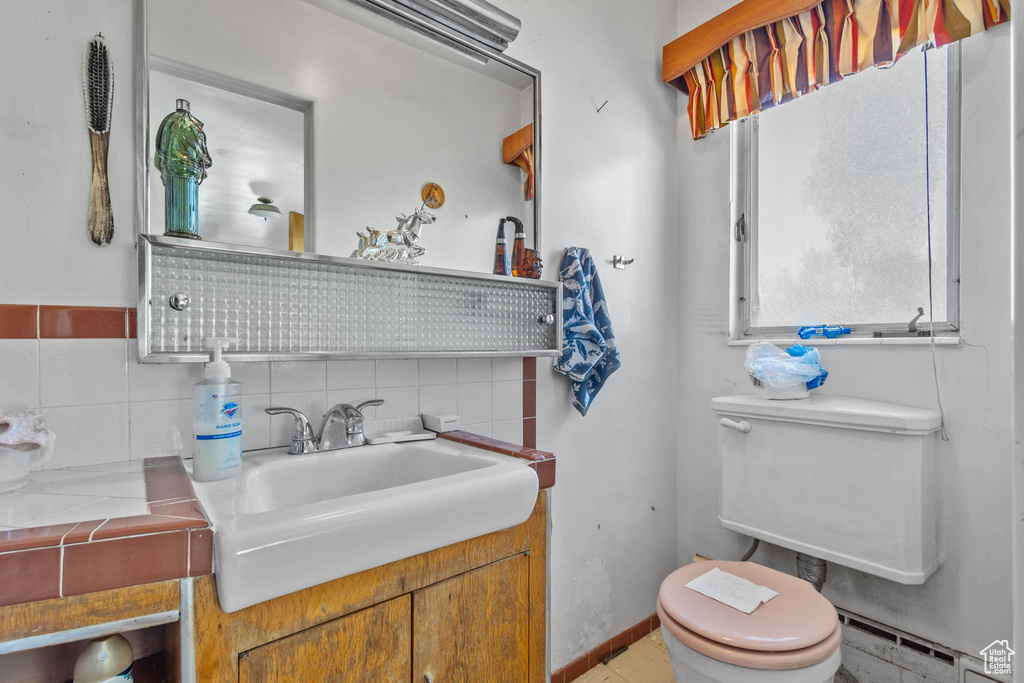 Bathroom with toilet, a baseboard heating unit, tasteful backsplash, and vanity