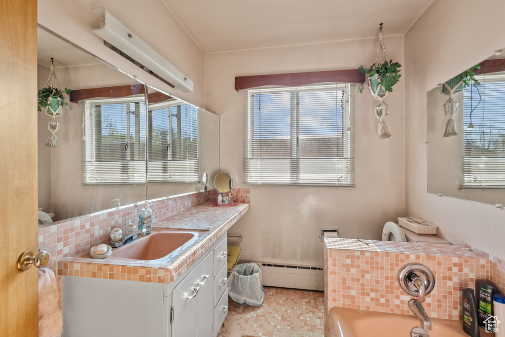 Bathroom featuring a garden tub, decorative backsplash, a baseboard radiator, and a healthy amount of sunlight