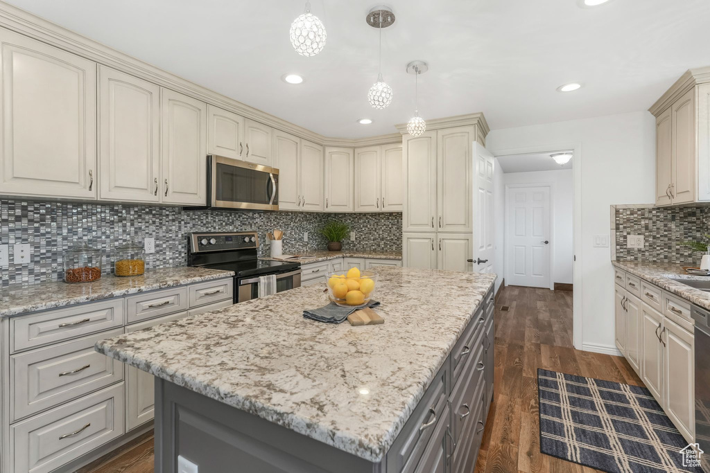 Kitchen featuring cream cabinets, dark wood-style flooring, gray cabinets, stainless steel appliances, and tasteful backsplash